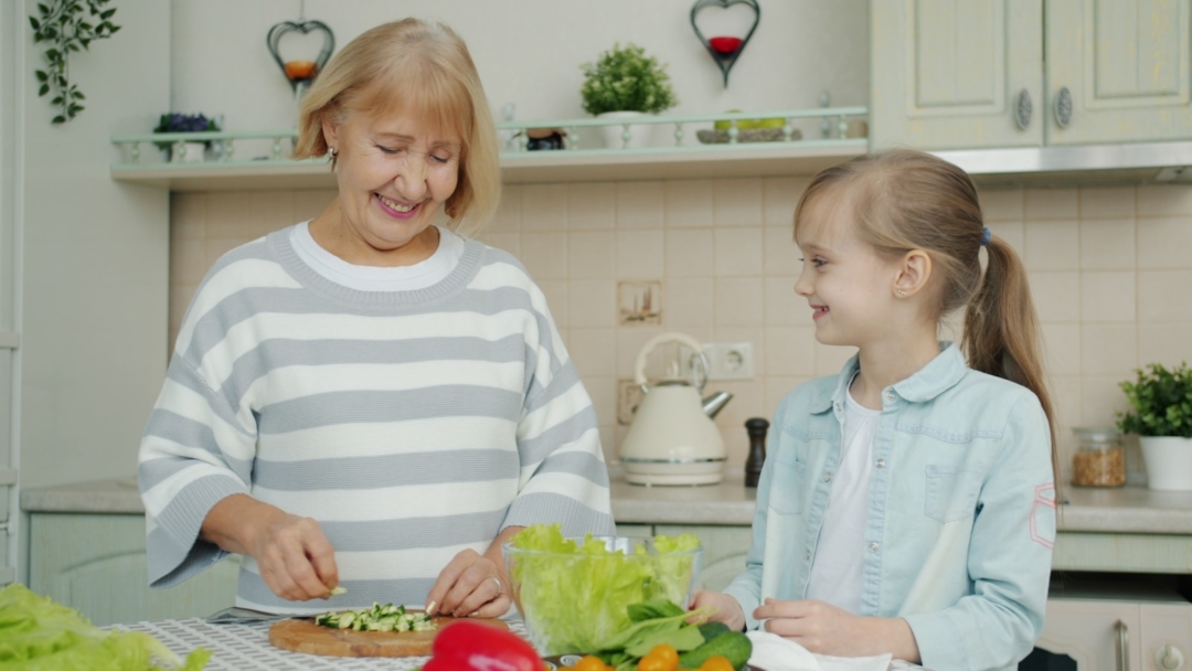 Grandmother and granddaughter preparing salad in kitchen